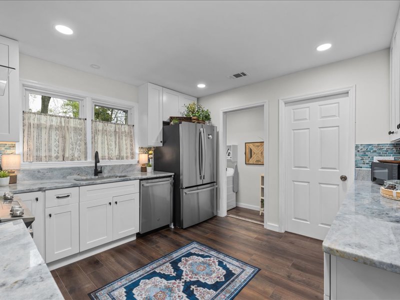 Artful Ansley kitchen with refrigerator, dishwasher, sink and white cabinetry