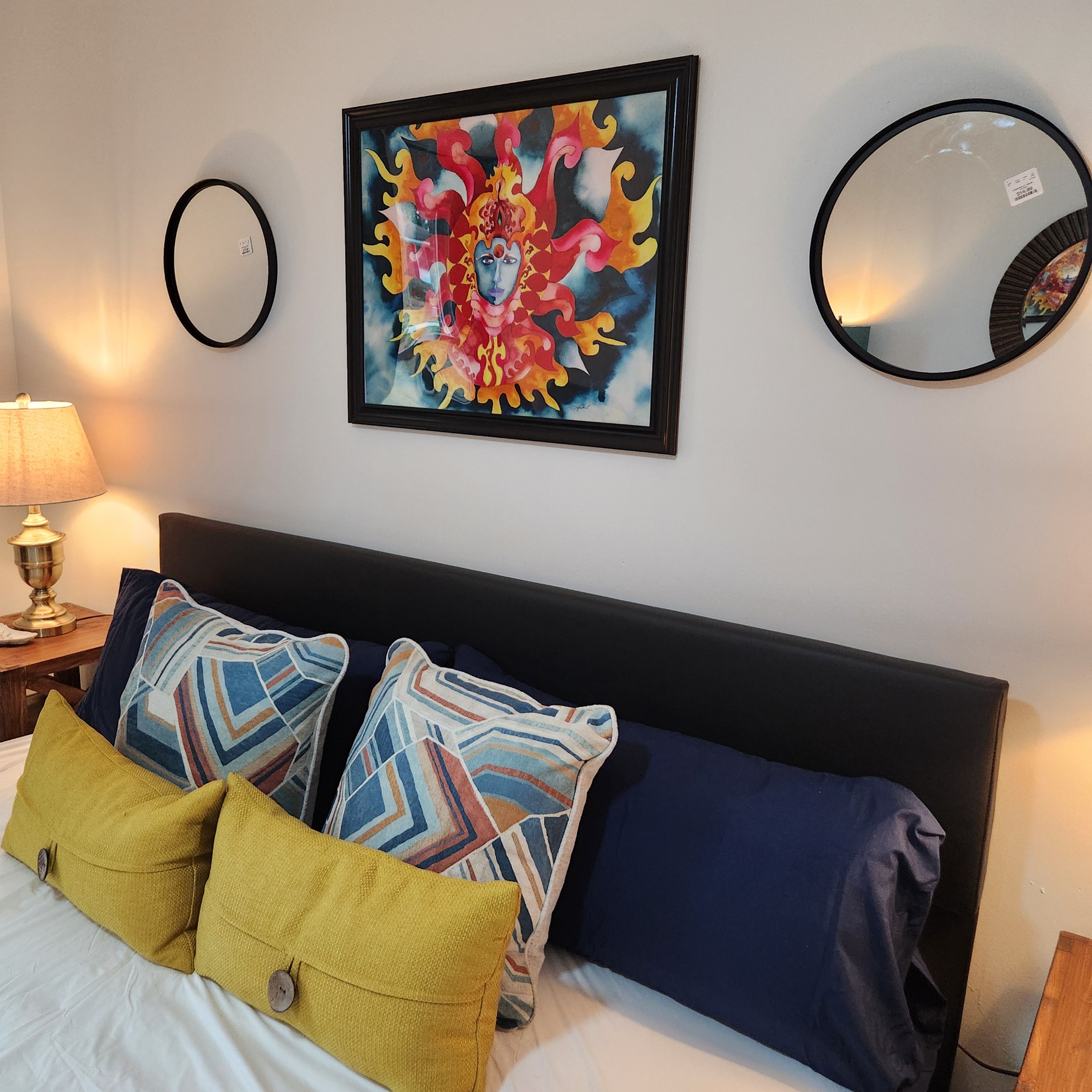 Colorful framed figurative artwork displayed above a bed at Artful Ansley